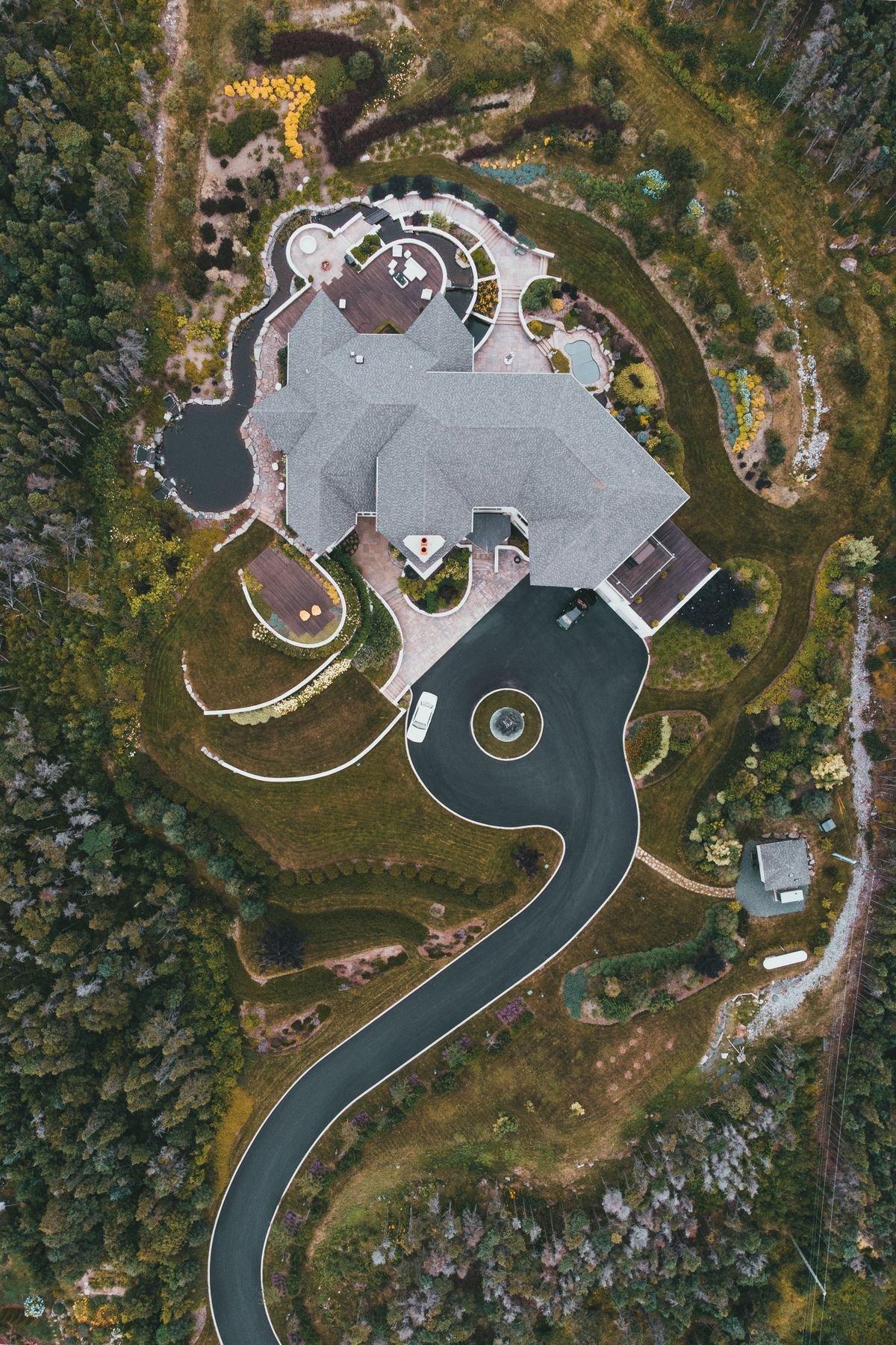 Aerial view of a house with landscaped gardens and a winding driveway