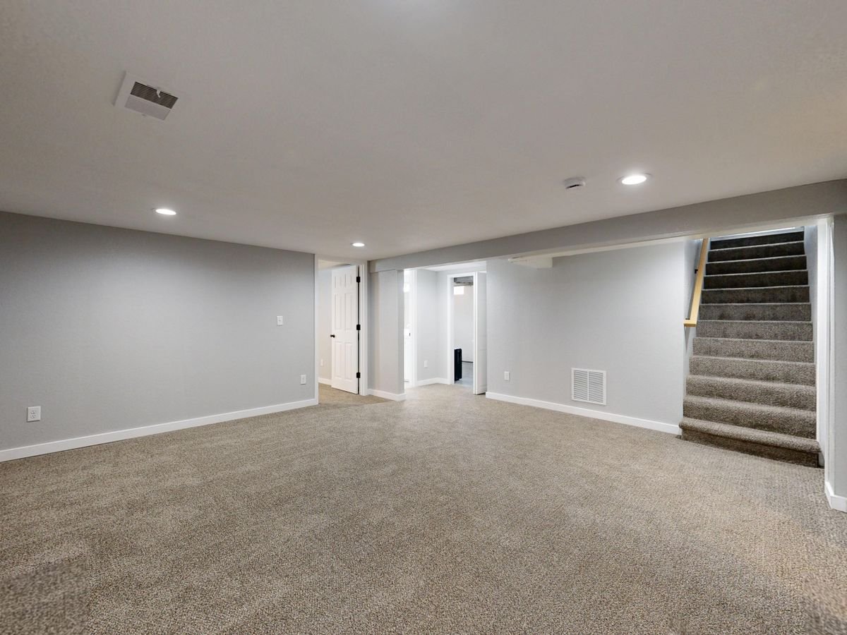 Empty modern basement with beige carpet and white walls