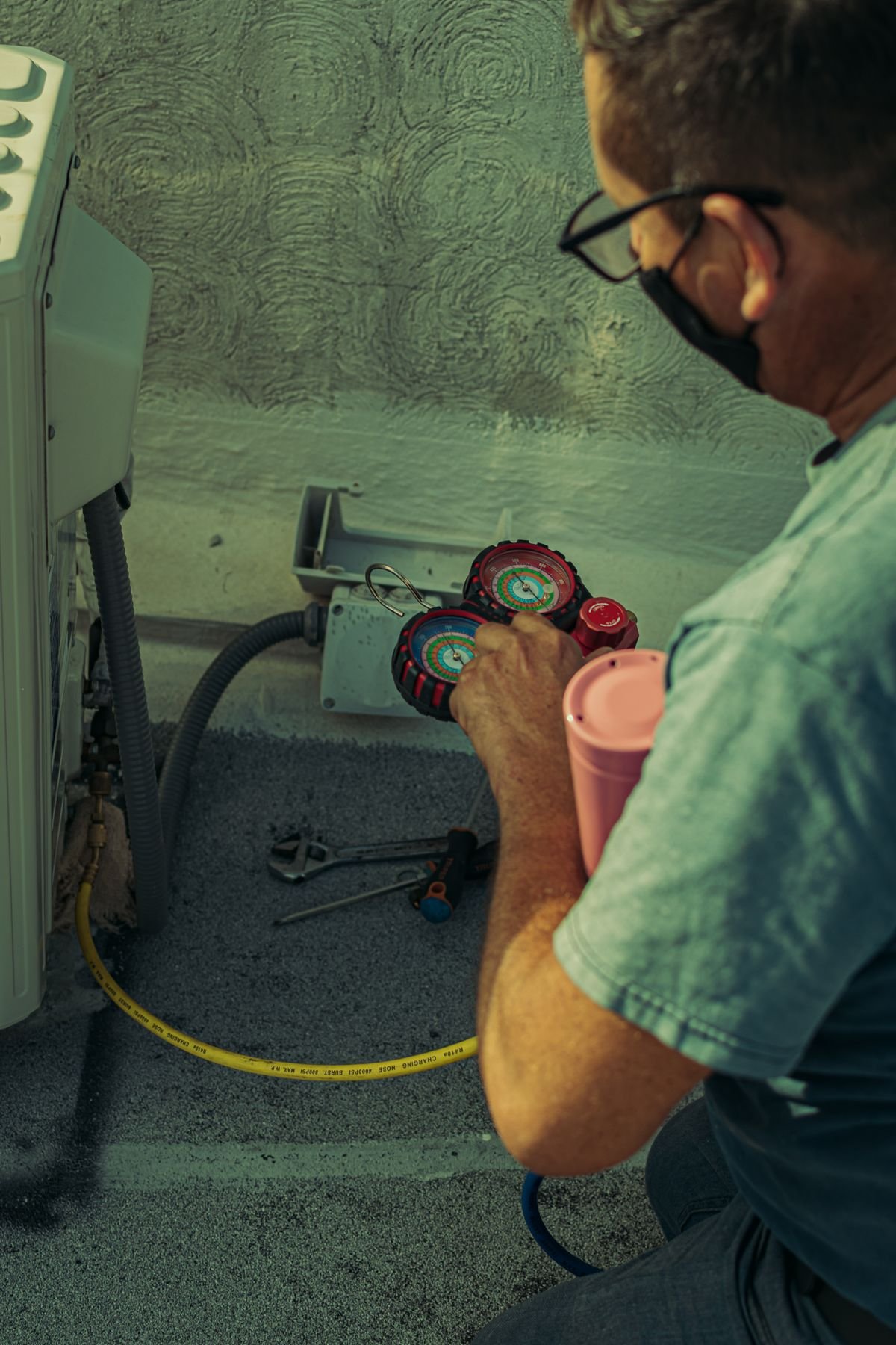 HVAC technician checking an outdoor condenser unit with gauges