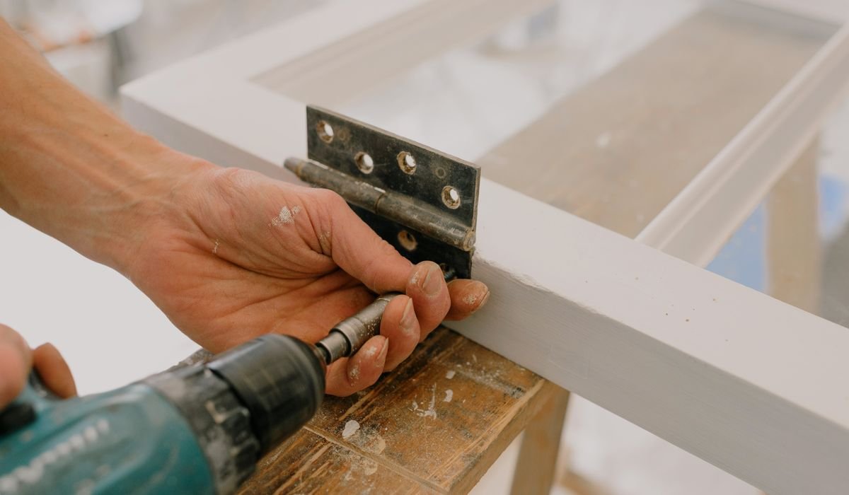 Installer fitting a cabinet panel with a cordless drill