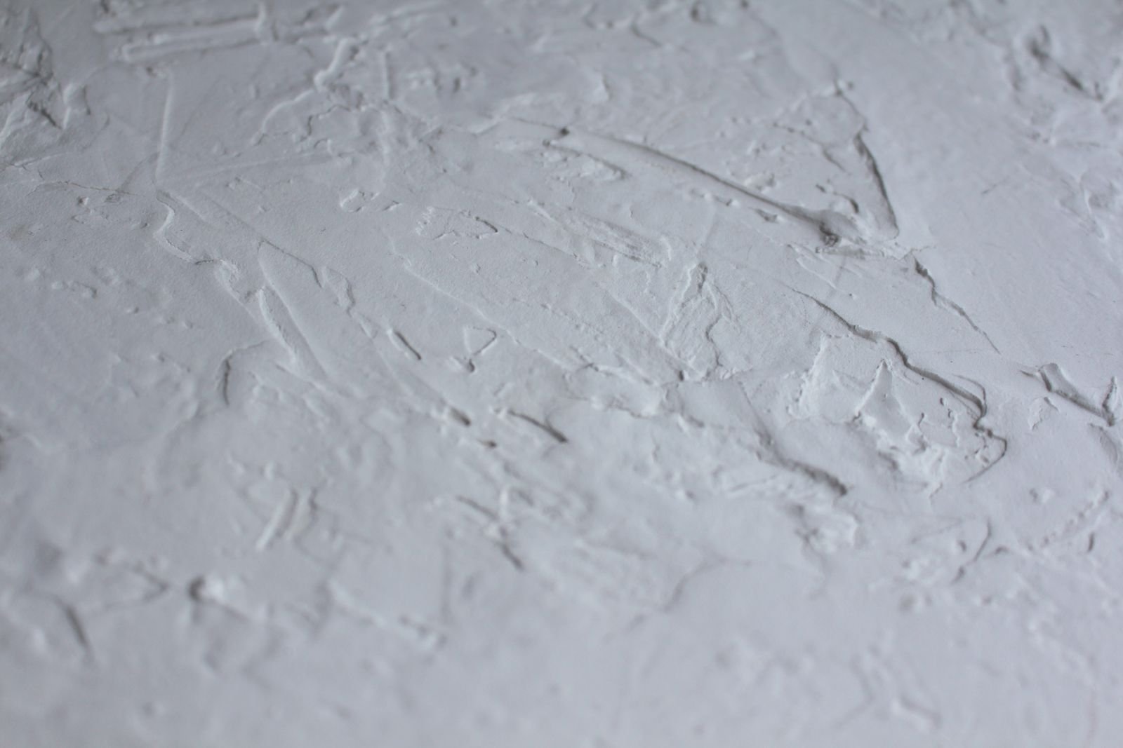 A worker skim-coating a ceiling smooth