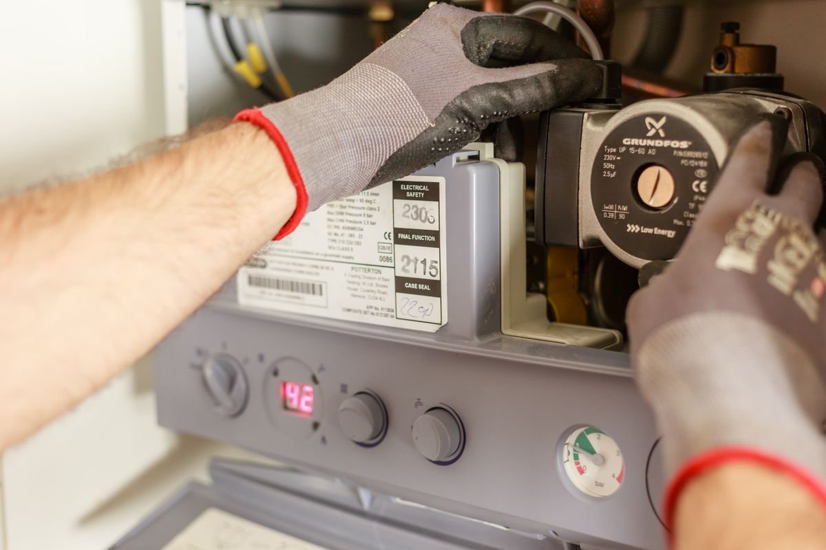 Hands adjusting the controls on a boiler water heater