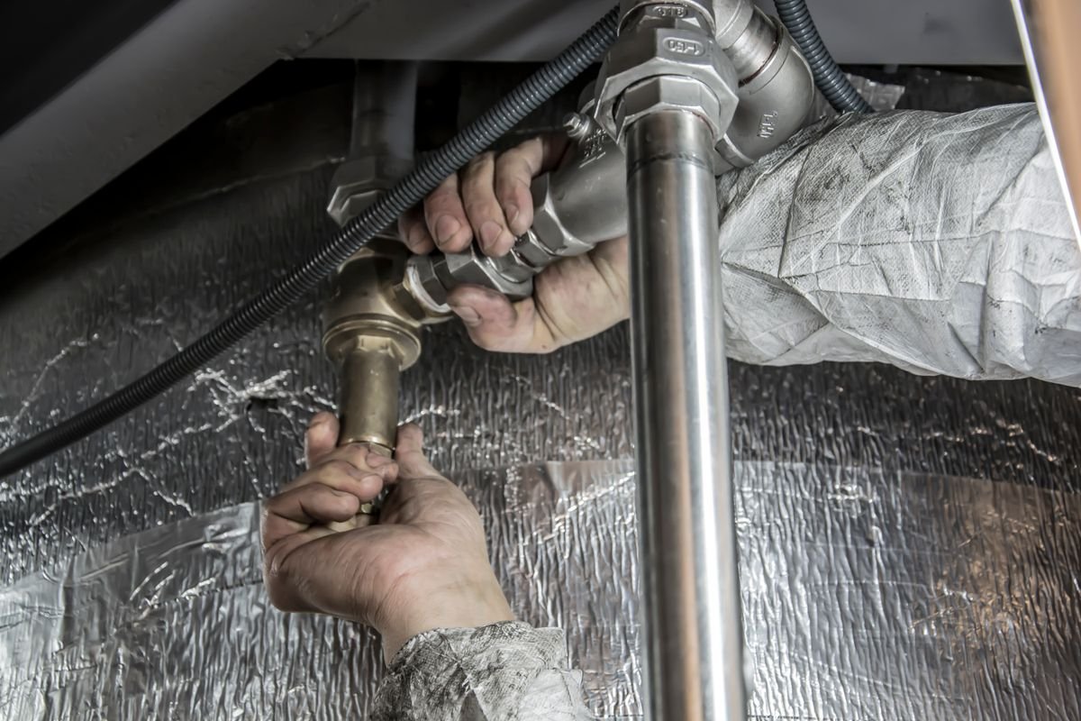 Plumber installing steel pipework indoors