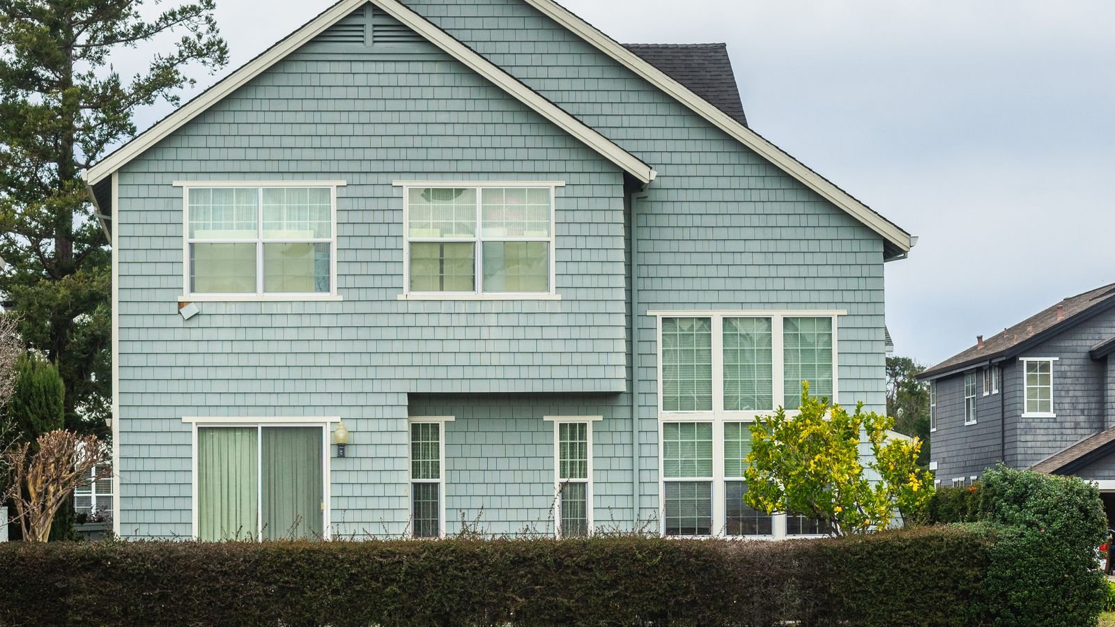 Two-storey house clad in pale blue lap siding with white trim