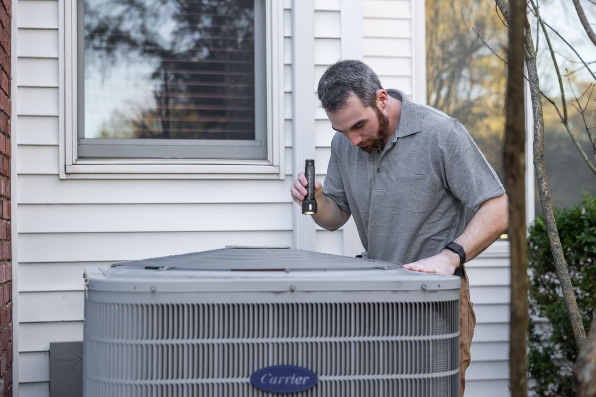 Technician inspecting an outdoor HVAC unit during maintenance