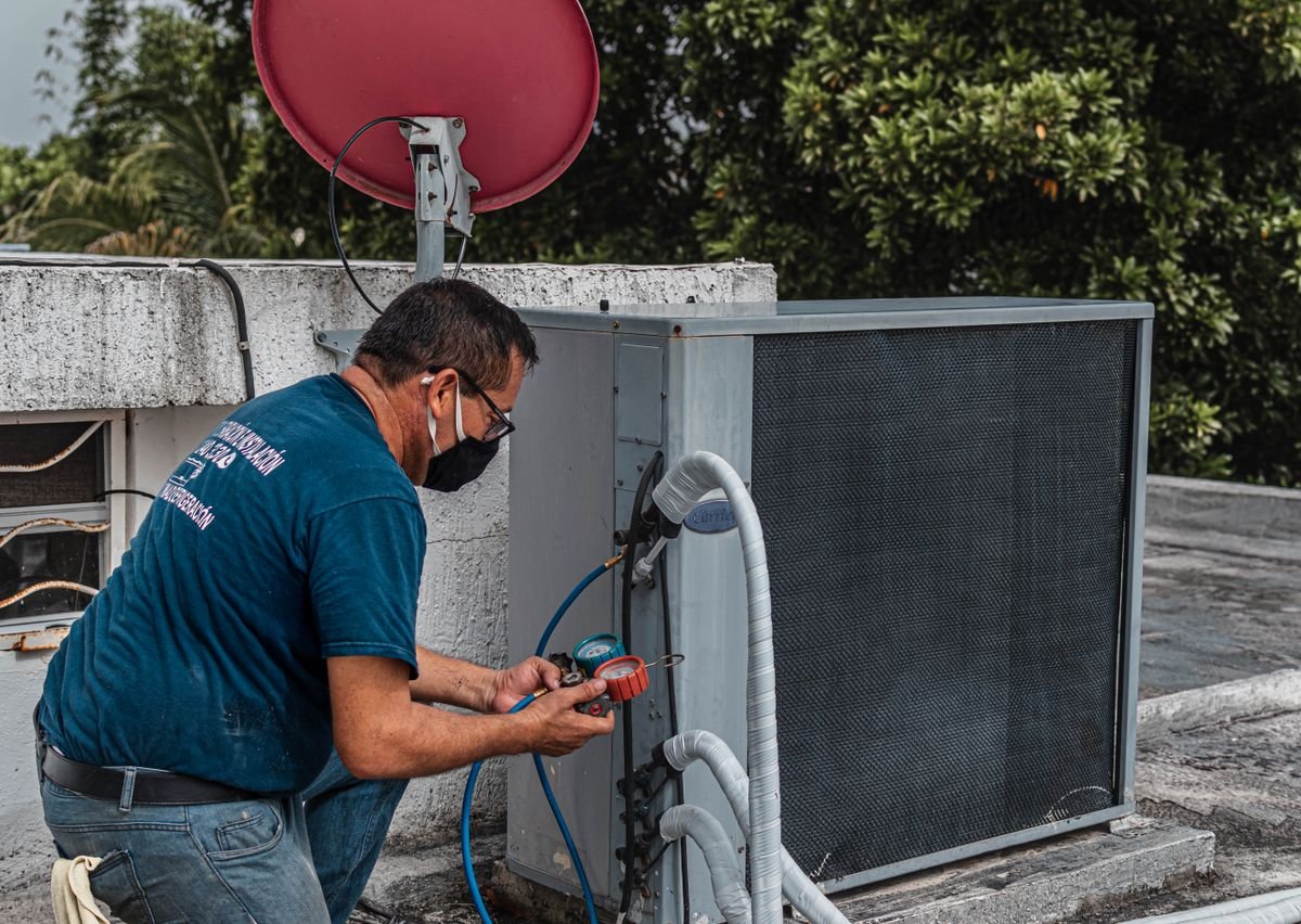 Technician repairing an air conditioning unit outdoors